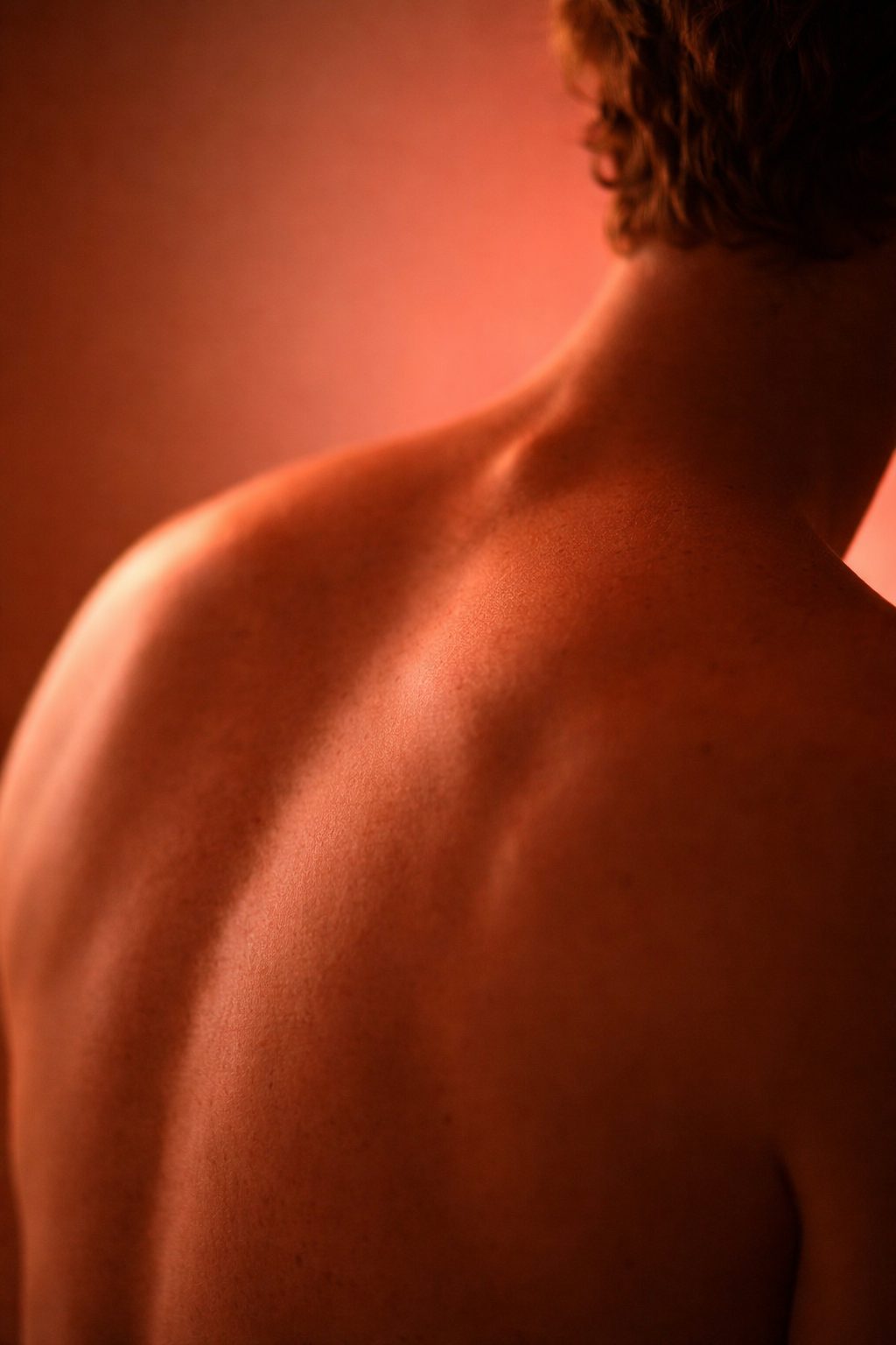 Person's shoulders and back bathed in warm red light